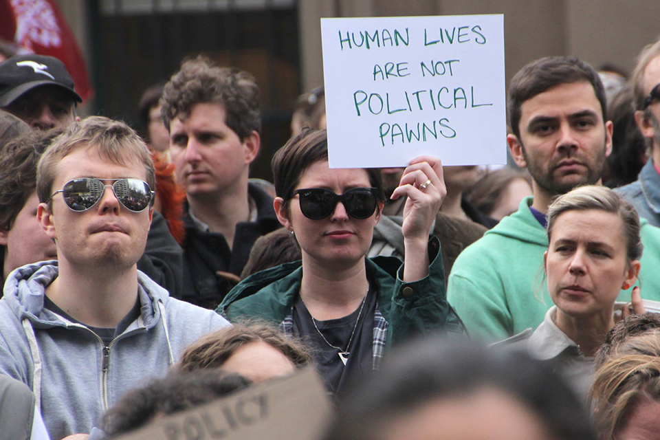 dynas yn dal arwydd - Human lives are not political pawns